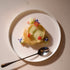 Small dessert in a nest with flowers on a white dessert plate with a spoon