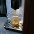Coffee being poured from a machine into a glass cup.