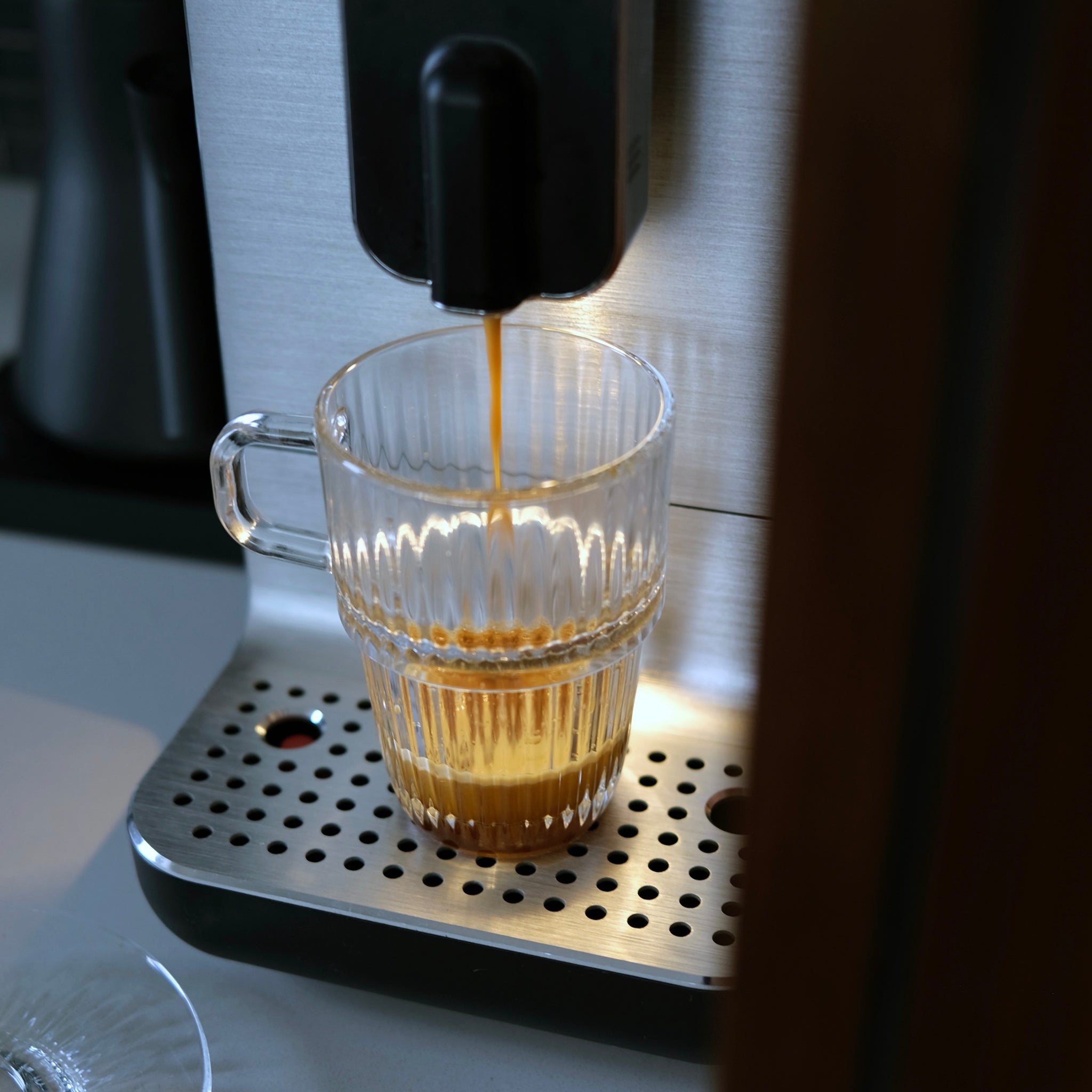 Coffee being poured from a machine into a glass cup.