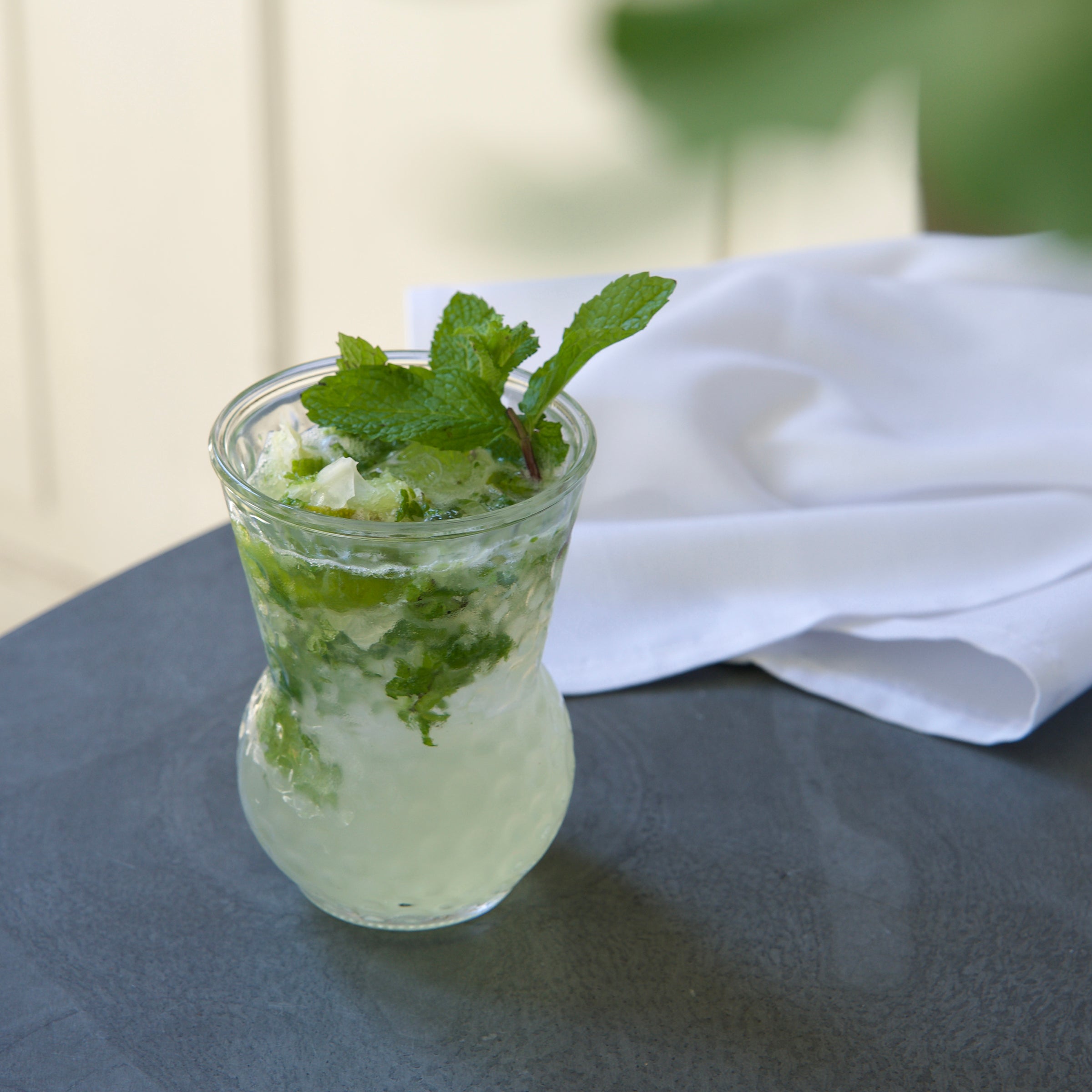 Bartender Mojito glass with Mojito cocktail with mint leaves on a dark surface with a white napkin.