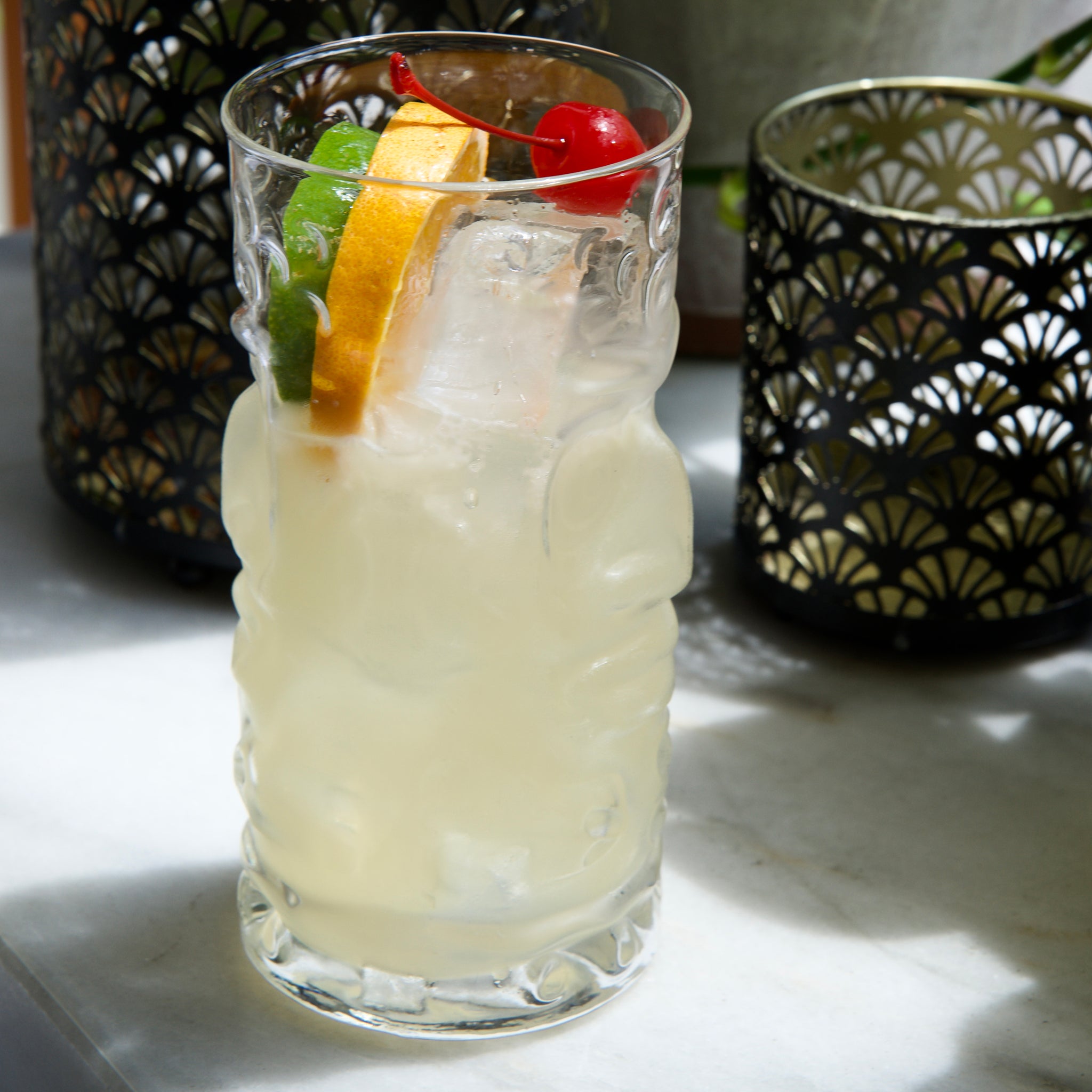 Bartender Tiki glass with a Tiki cocktail with ice and garnishes in a glass on a marble surface