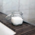 Clear glass jar with a lid containing white powder on a wooden surface.
