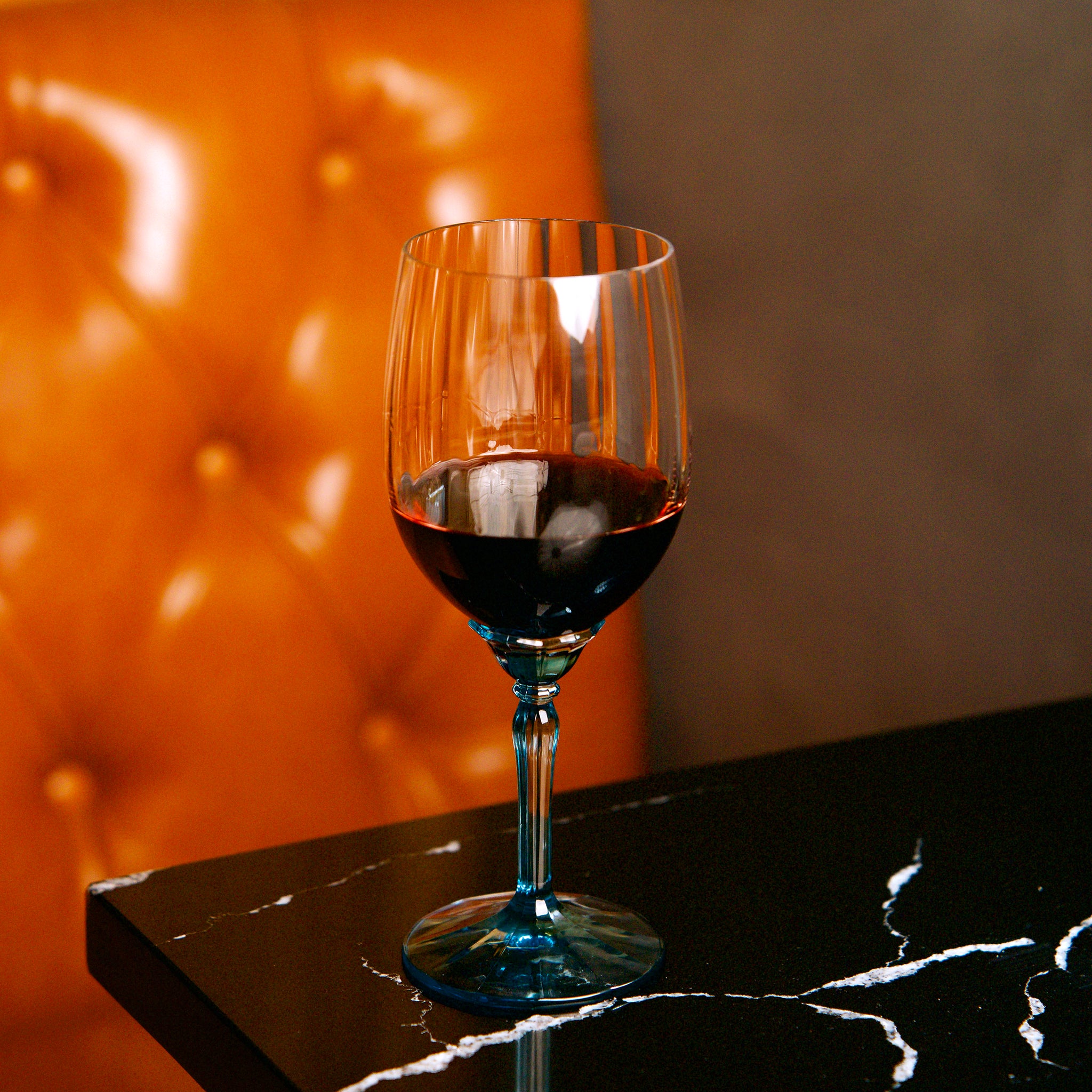Florian Red wine glass with red wine on a dark surface with an orange background