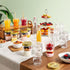 Table with Quattro Stagioni special edition jars of assorted drinks and snacks against a light green wall.