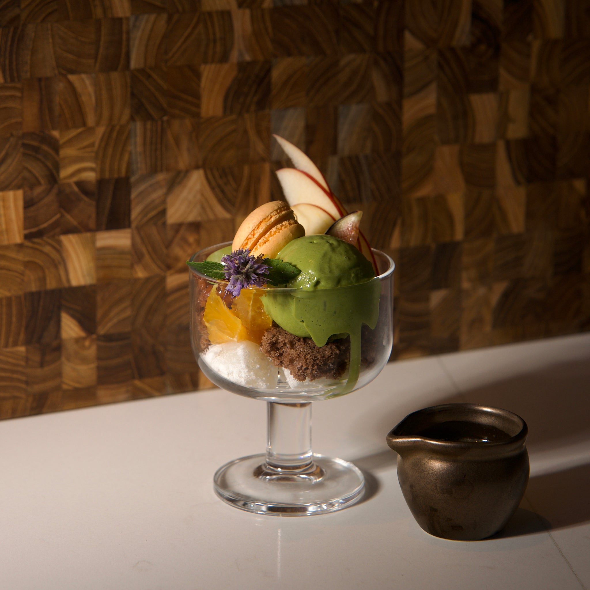 Dessert with ice cream and fruits in a glass bowl on a wooden surface